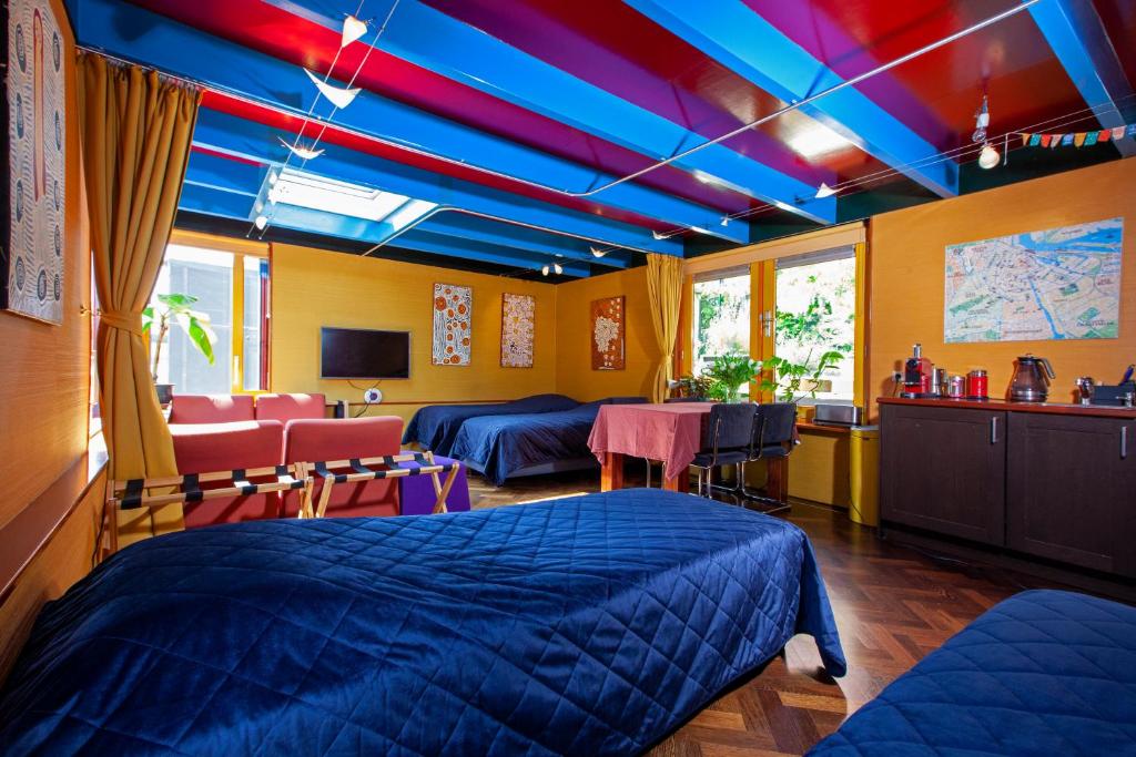 een kamer met 2 bedden en een tafel en stoelen bij Dreamtime Houseboat in Amsterdam