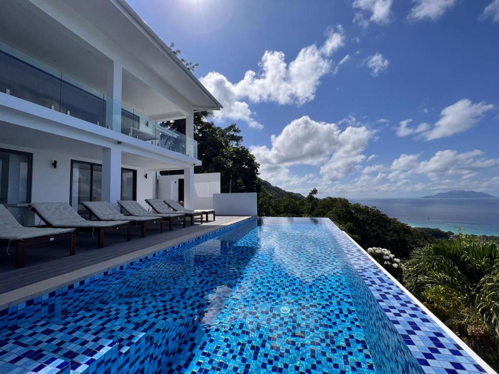 a villa with a swimming pool with a view of the ocean at Paradise Heights Luxury Apartments & Villa in Beau Vallon