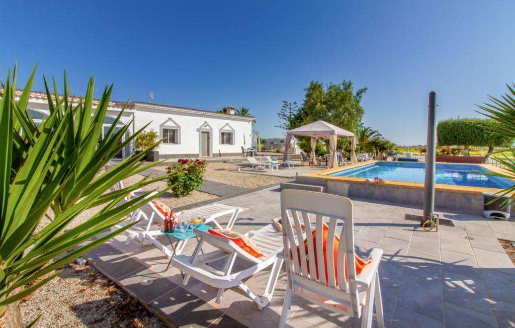 un patio con 2 sillas y una mesa junto a la piscina en Exceptional Rico's Country Retreat Almendricos, en Puerto Lumbreras