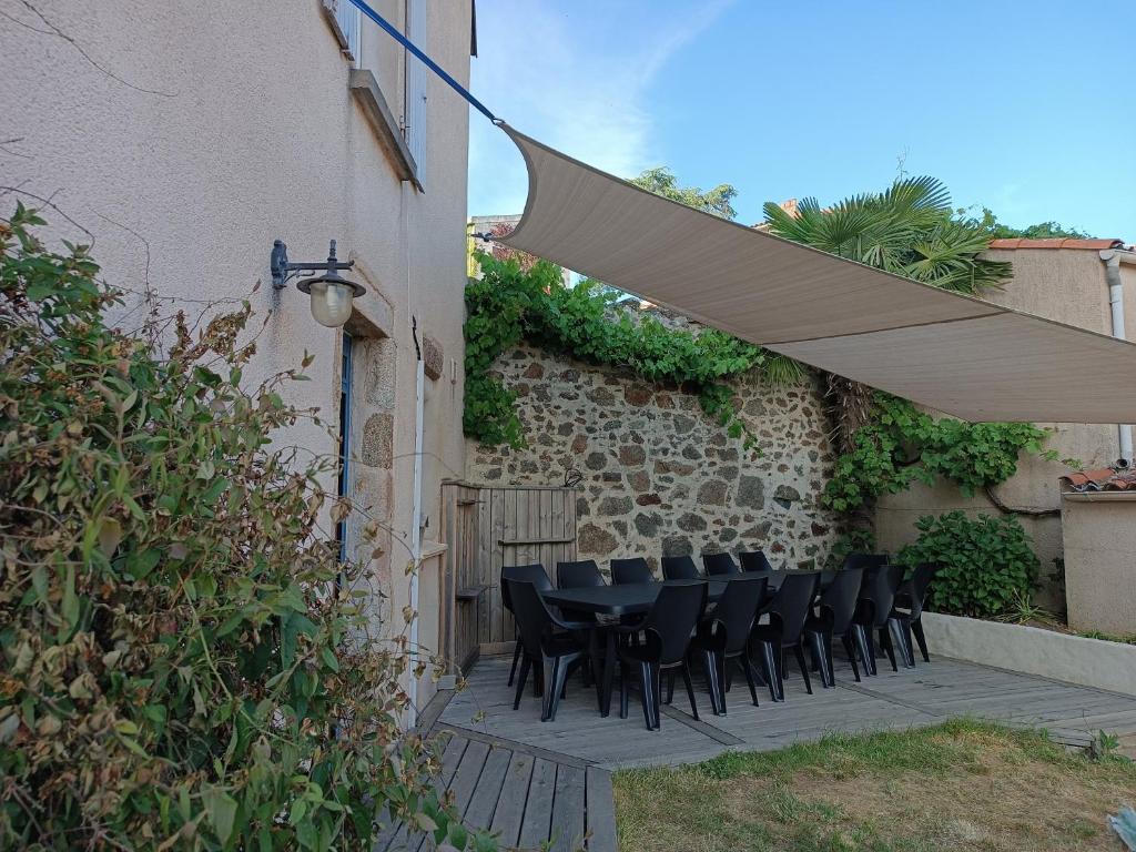 patio con tavolo e sedie sotto ombrellone di Gîte 14 personnes à proximité du Puy du Fou "Bonheur à l' Aubépin" à 18 minutes du célèbre parc a Pouzauges