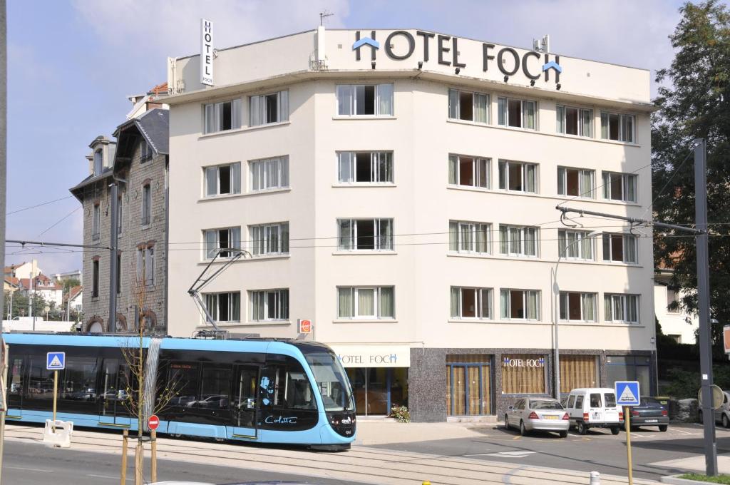 a blue bus on a street in front of a hotel at Contact Hôtel Foch in Besançon