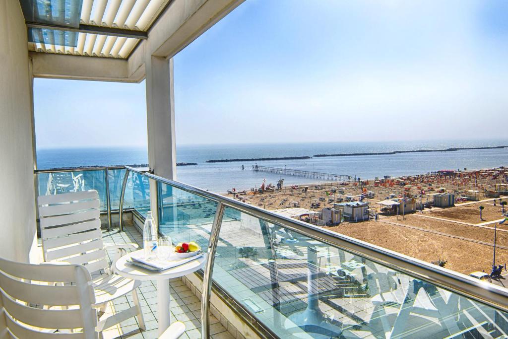 balcón con mesa y sillas y playa en Hotel Gorini, en Bellaria-Igea Marina