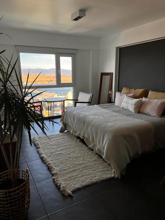 a bedroom with a large bed with a large window at LiveUshuaia Beagle View in Ushuaia