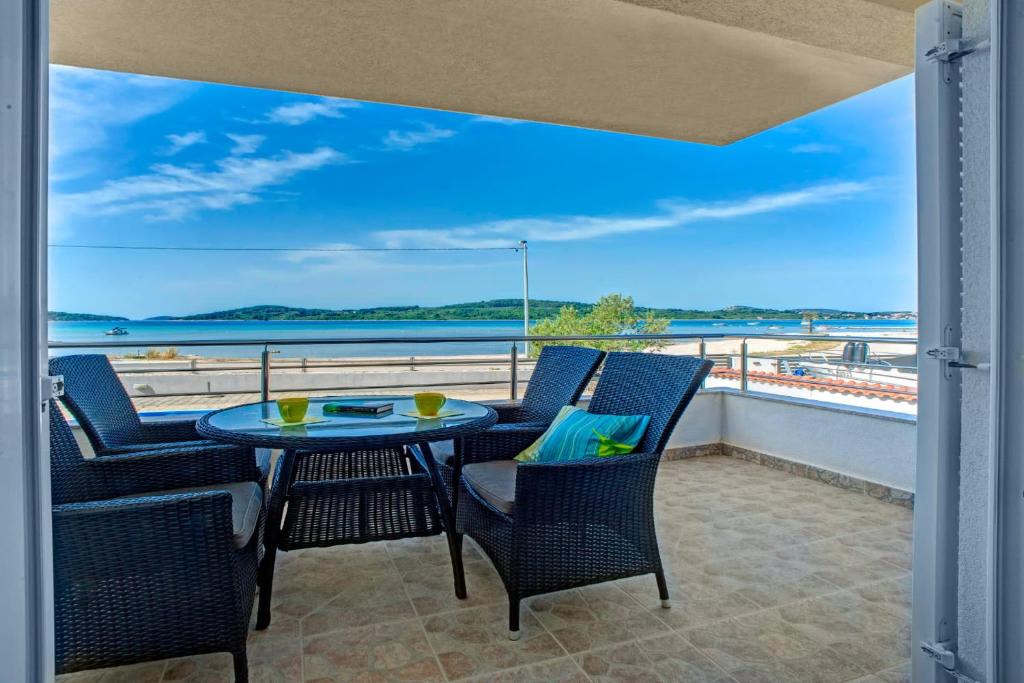 een balkon met een tafel en stoelen en uitzicht op de oceaan bij ERE Apartment in Srima