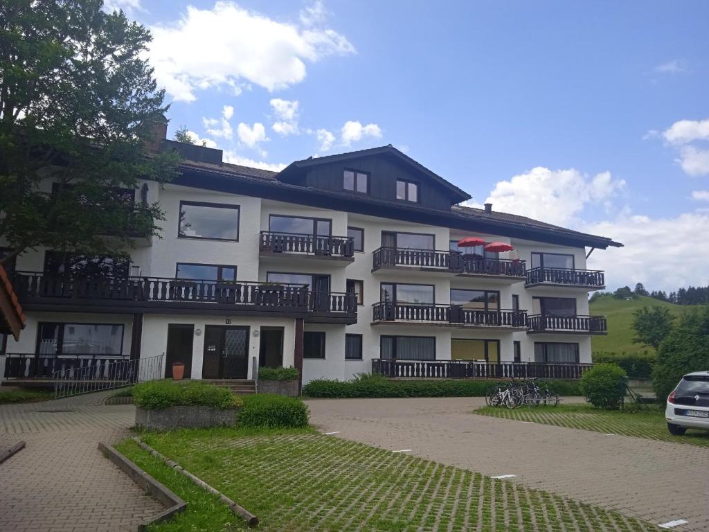 a large white building with balconies and a parking lot at Appartement 223 in Füssen