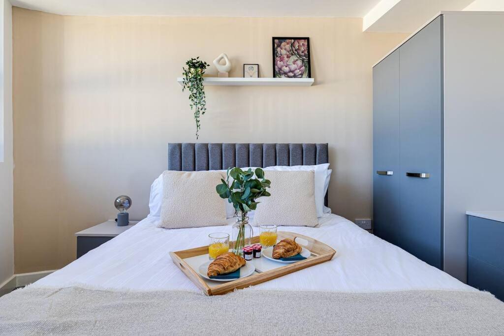 a tray of food on a bed with two drinks at Entire 1 bed apt in the centre of Stockport in Stockport