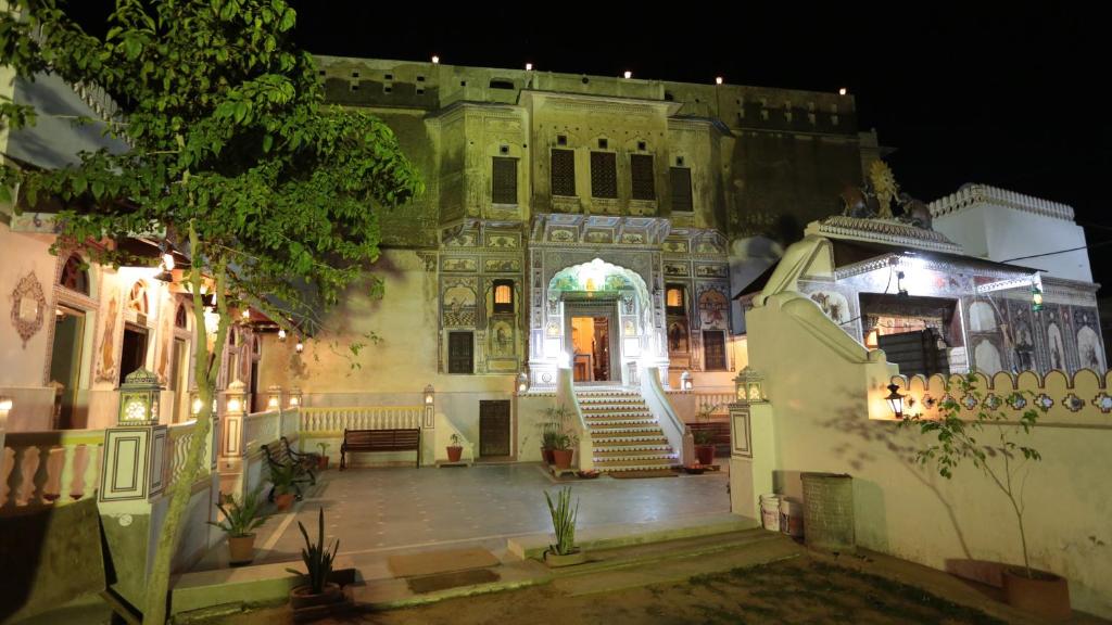 un ancien bâtiment avec un escalier devant lui la nuit dans l'établissement Hotel Radhika Haveli, Mandawa, à Mandāwa