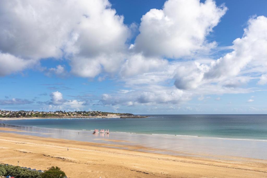 a beach with a group of people standing in the water at L'Ar Timon in Saint-Cast-le-Guildo