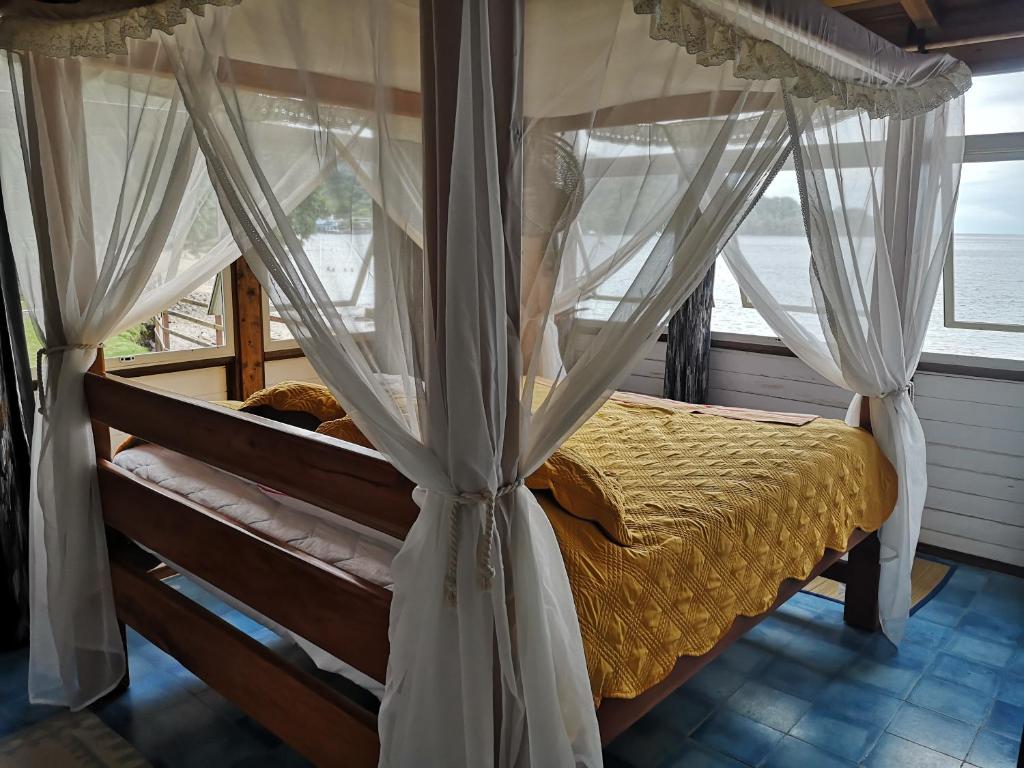 ein Schlafzimmer mit einem Himmelbett und einem Fenster in der Unterkunft Cafe del Mar Sapzurro in Zapzurro
