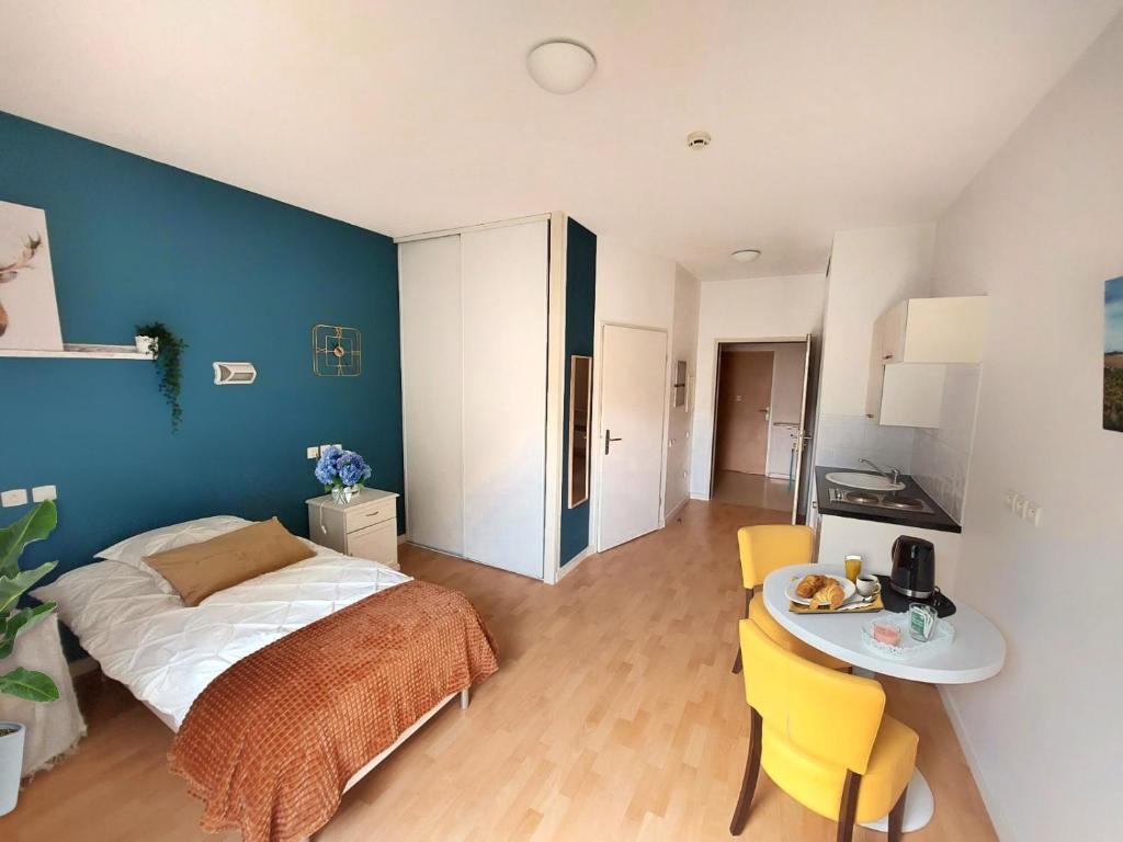 a bedroom with a bed and a table in it at Villa Rose de Mons - Résidence Services Senior in La Brede