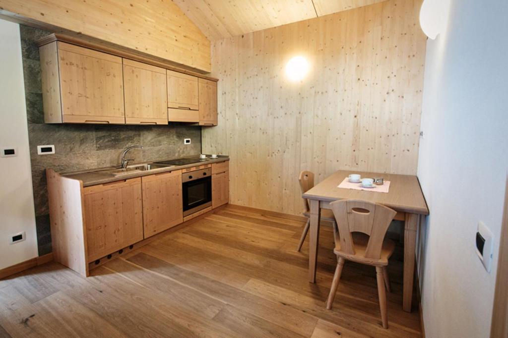 una cucina con armadi in legno e tavolo con sedie di La Marmote Albergo Diffuso di Paluzza Ronc a Paluzza