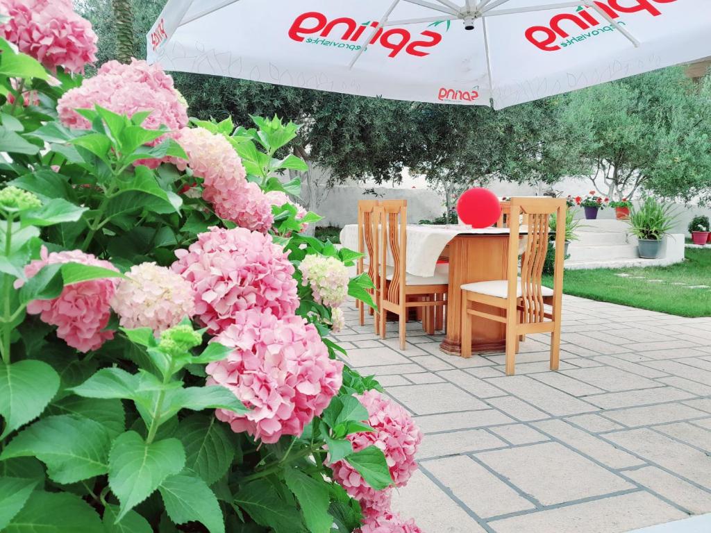 einen Tisch und Stühle mit rosa Blumen und einem Regenschirm in der Unterkunft GB Rooms in Ksamil