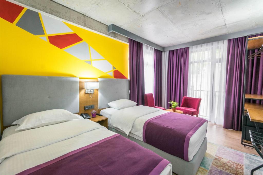 Habitación de hotel con 2 camas y techo colorido. en Hotel Adora, en Tiflis
