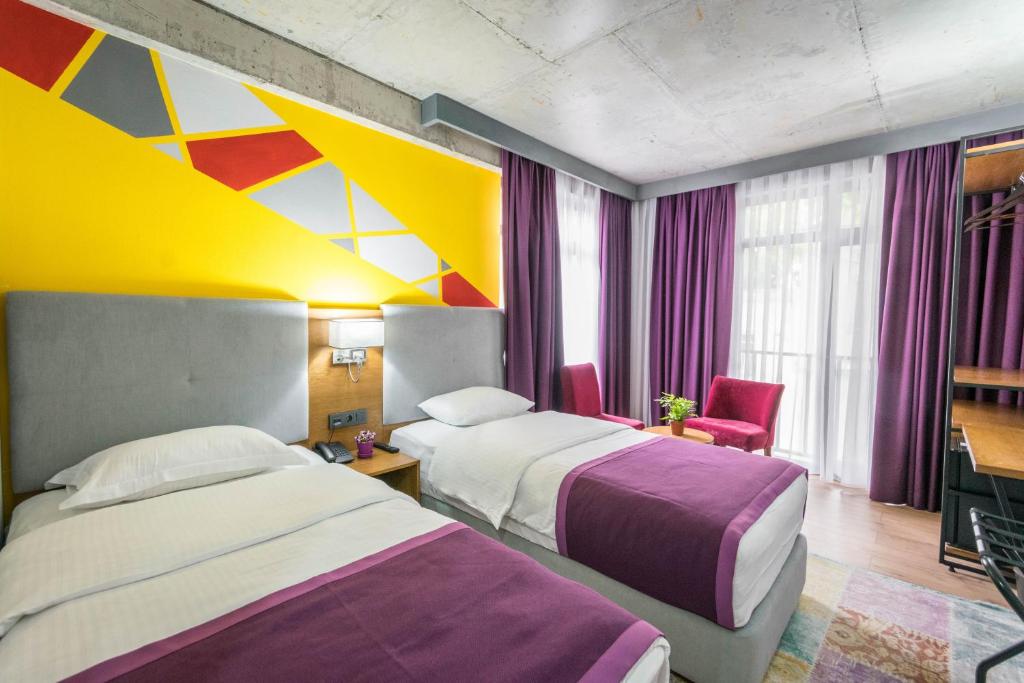 a hotel room with two beds and a colorful ceiling at Hotel Adora in Tbilisi City