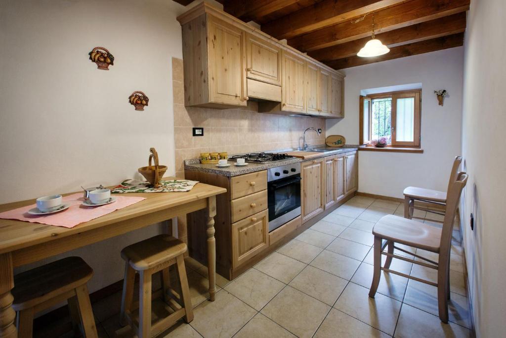 una cocina con armarios de madera y una mesa con sillas. en La Marmote Albergo Diffuso di Paluzza Clome, en Paluzza