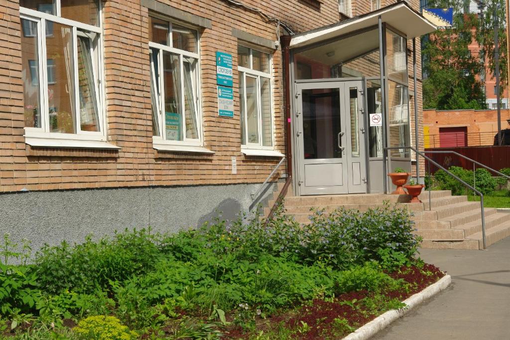 una casa de ladrillo con una puerta blanca y escaleras en Karelrepostrebsoyuz Hostel, en Petrozavodsk