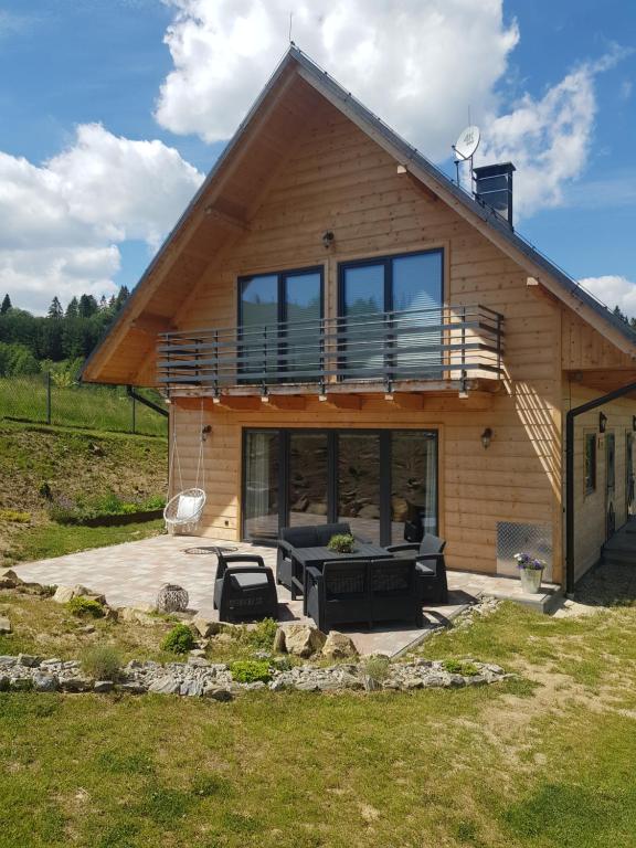 a house with a deck and a patio in front of it at Domki Cztery Pory Roku in Łapsze Niżne