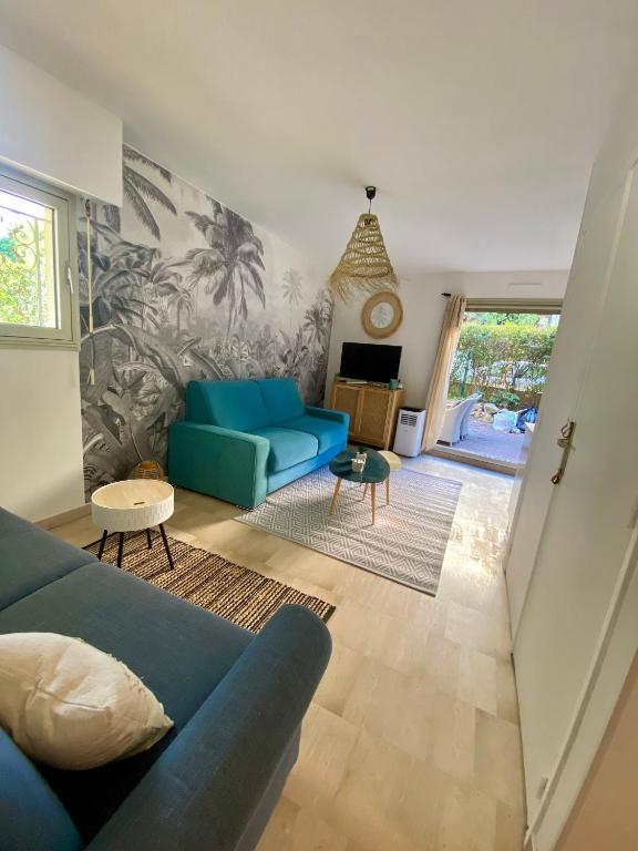 un salon avec un canapé bleu et une table dans l'établissement La Beau'M Juan Les Pins centre ville 200m de la mer terrasse et jardin, à Juan-les-Pins