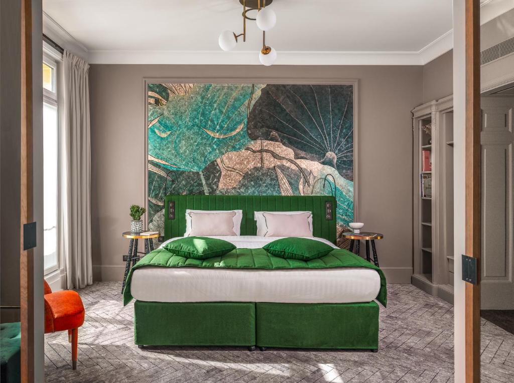 M Social Hotel Paris Opera في باريس: غرفة نوم بسرير اخضر مع لوحة على الحائط