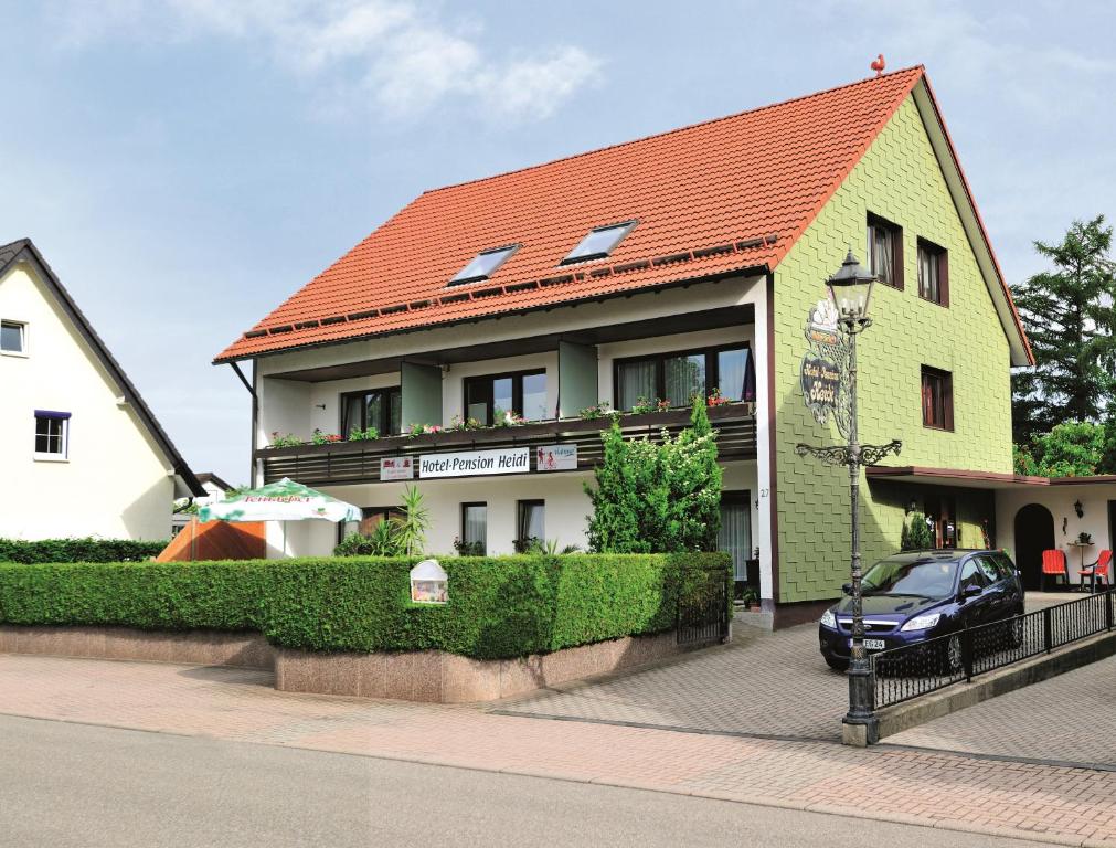 une maison jaune avec un toit orange dans l'établissement Hotel Pension Heidi, à Dobel