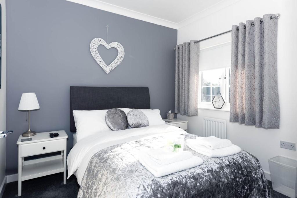 a bedroom with a bed with a heart plaque on the wall at Riverside Stays, Shefford in Shefford