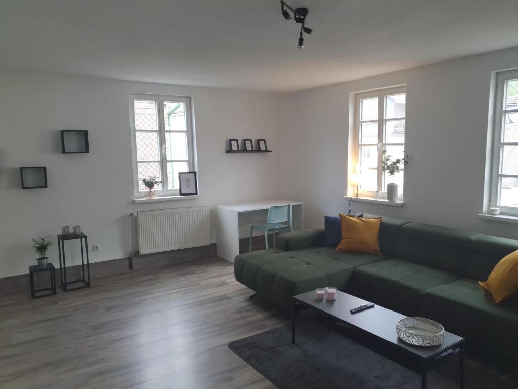een woonkamer met een groene bank en een tafel bij Gemütliche Wohnung *zentral* *Netflix* *Parkplatz* in Bad Laasphe
