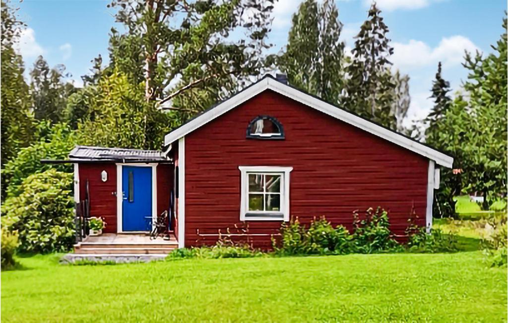 een rood huis met een blauwe deur op een groen veld bij Awesome Home In Dalahusby With Kitchen in Dala Husby