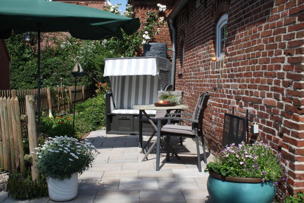 un patio con mesa, silla y sombrilla en Apartment Vier Jahreszeiten Pilsum en Krummhörn