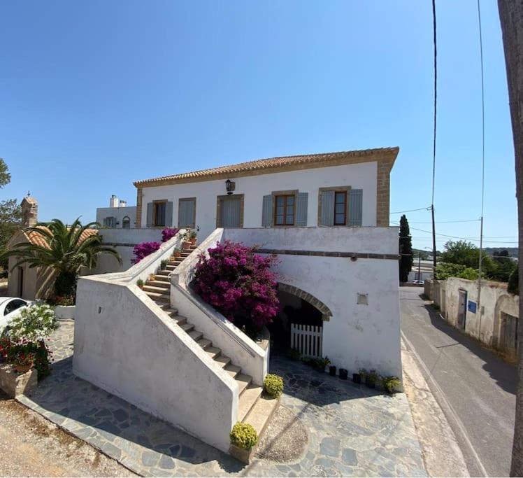 a white house with stairs and flowers in front of it at Vranadika in Livadi