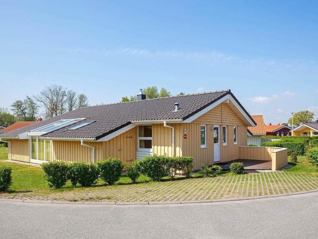 ein Holzhaus mit einem Dach auf einer Straße in der Unterkunft 12 person holiday home in GROEMITZ in Grömitz