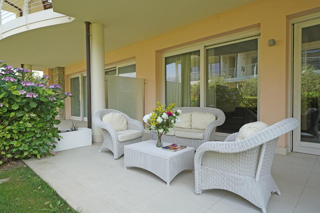 Un patio con sillas de mimbre y una mesa con flores. en Giulia Luxury Apartment, en Sirmione