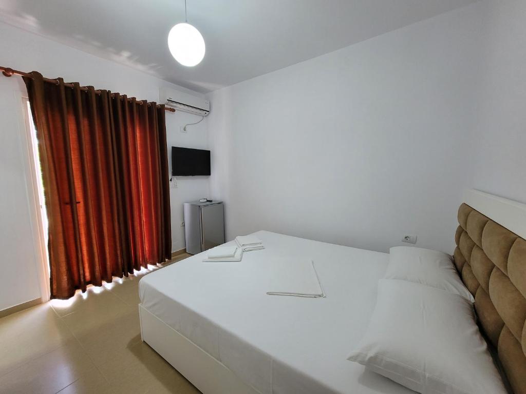 a bedroom with a white bed and a red curtain at Vila Geri in Ksamil