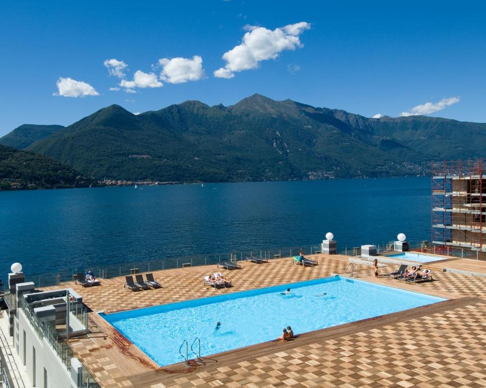 a swimming pool on top of a building next to a body of water at Golfo Gabella Lake Resort in Maccagno Superiore