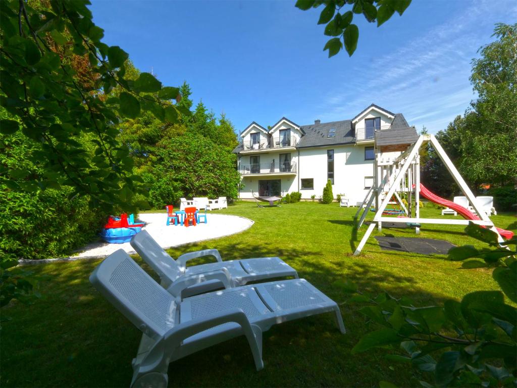 a yard with two blue chairs and a playground at Willa Liliowa in Dębki