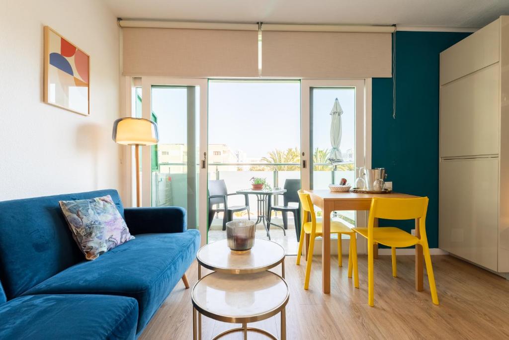 een woonkamer met een blauwe bank en een tafel bij Trendy, very well located apartment in Playa del Inglés