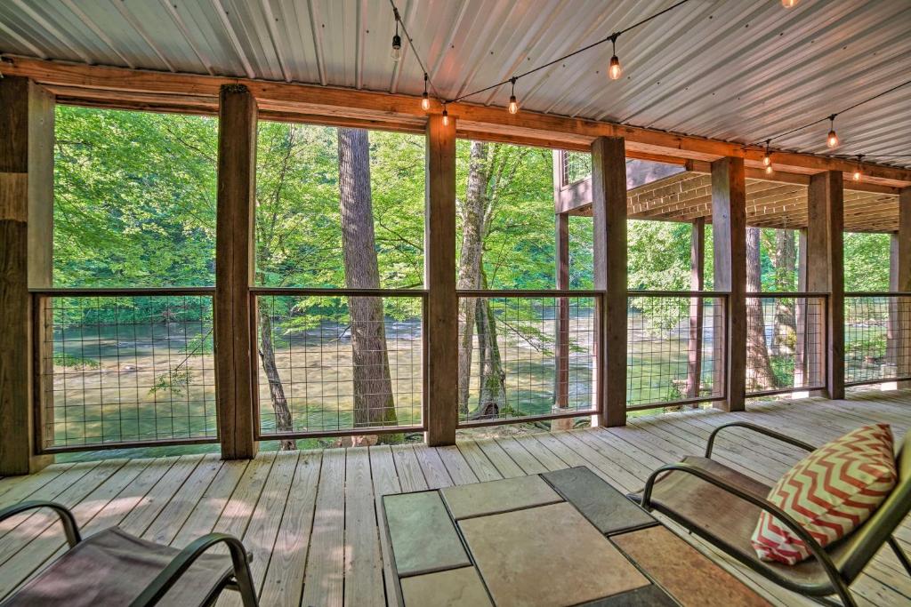 un porche cubierto con sillas y ventanas en Crystal River Cabin with Scenic View and Fire Pit, en Walland