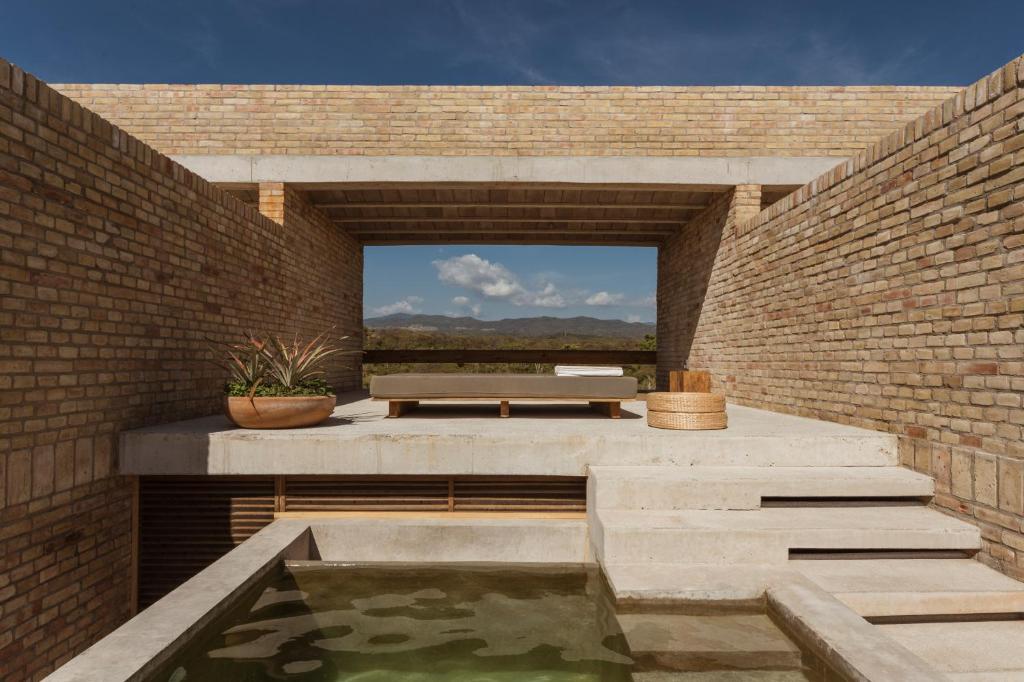 a brick patio with a pond and a bench at Terrestre, a Member of Design Hotels in Puerto Escondido