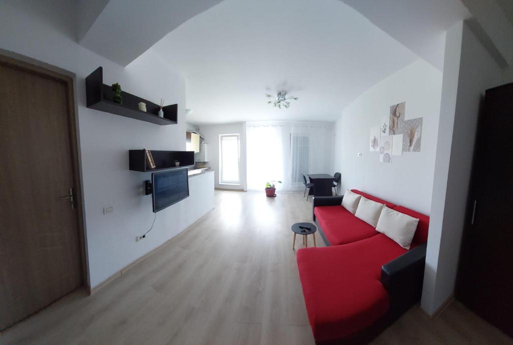 sala de estar con sofá rojo y pared blanca en Garsoniera Studio, en Constanţa