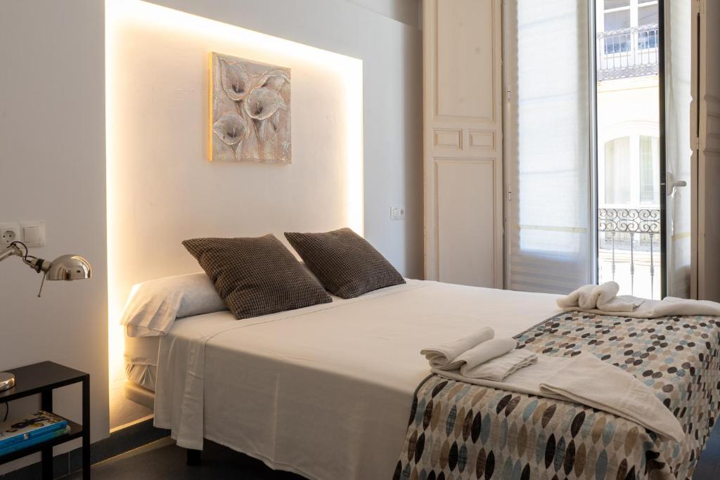 una camera da letto con un grande letto bianco e una finestra di Mar y Arte Apartamentos a Málaga