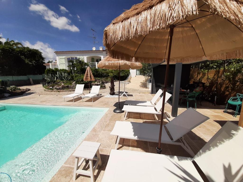 a swimming pool with chairs and umbrellas next to a pool at VILLA RASOA chambre LIBELLULE in Cap d&#39;Agde