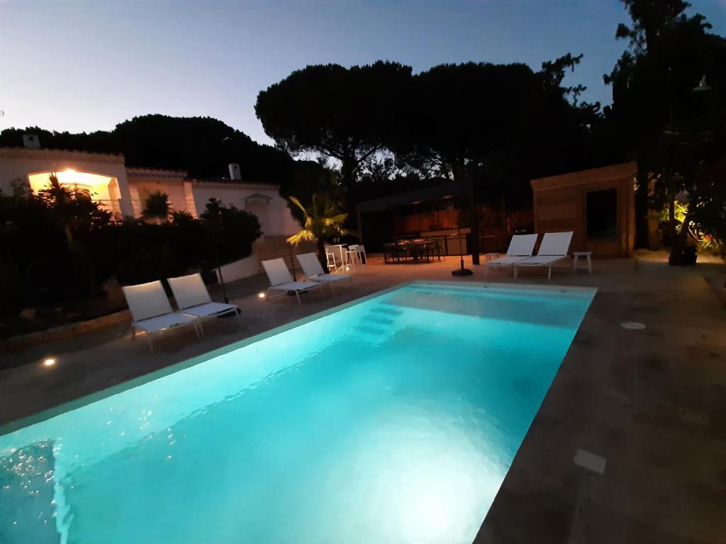 a large swimming pool with chairs and a house at VILLA RASOA chambre LIBELLULE in Cap d&#39;Agde