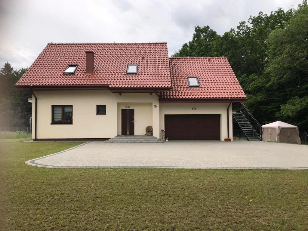 a house with a red roof and a garage at Apartament Mazurski Rodowo in Sorkwity