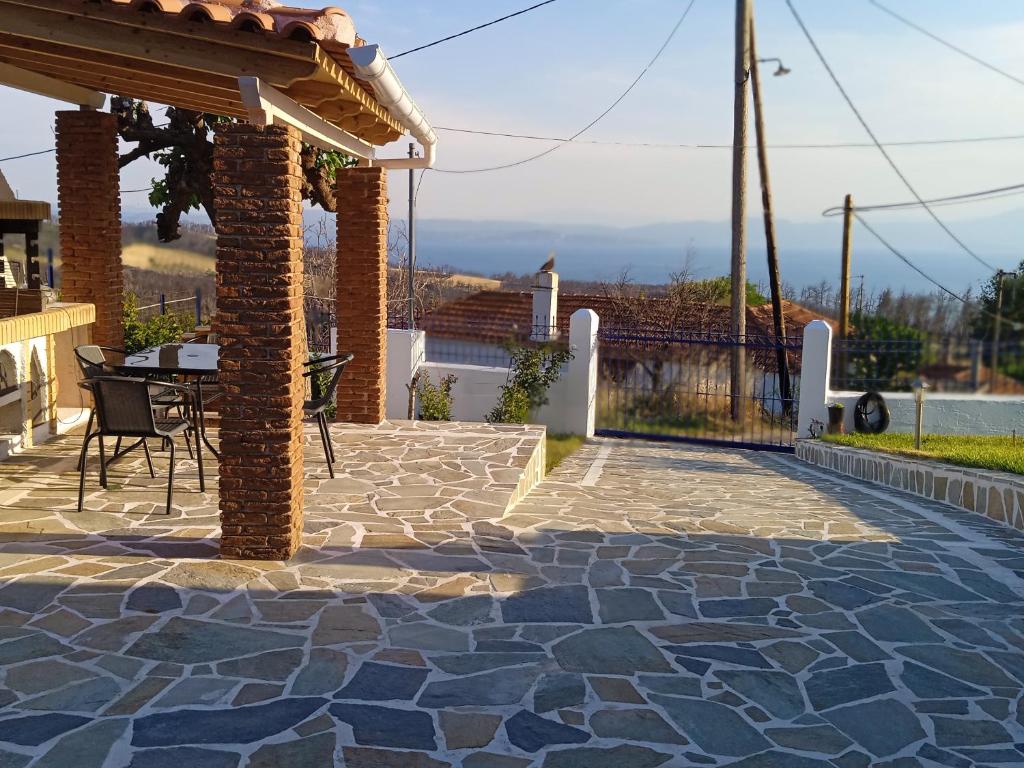a patio with a table and chairs on a stone patio at Σπίτι στο βουνό αλλά μια ανάσα από τη θάλασσα in Palaiokhórion