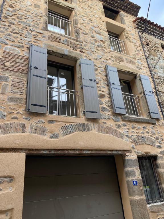 a building with blue shuttered windows and a garage at Appartements neufs avec garages dans maison de village in Andance
