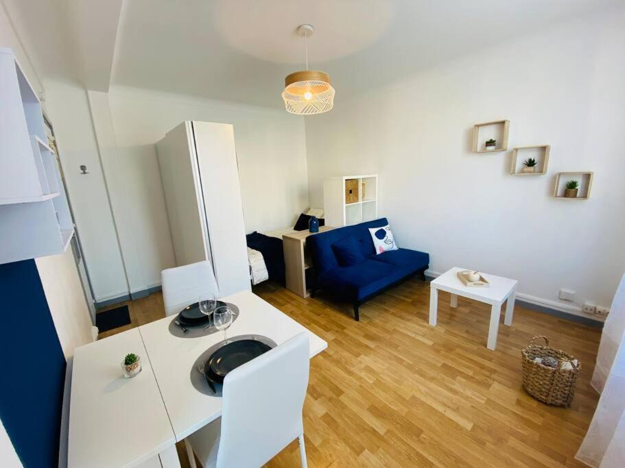 a living room with a blue couch and a table at Superbe studio au pied de la gare de Caen in Caen