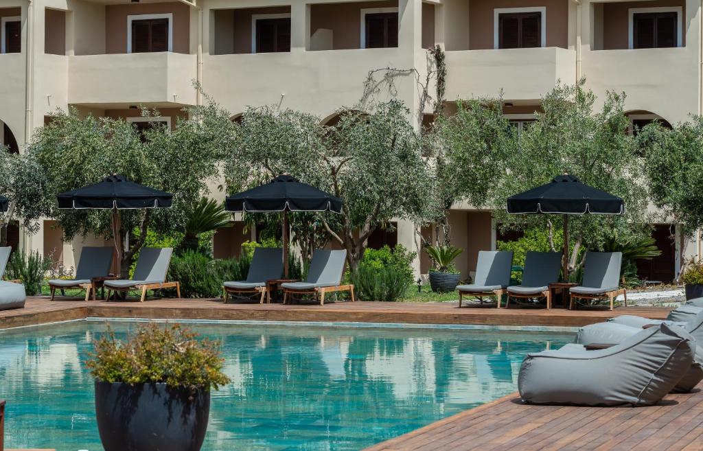 uma piscina do hotel com cadeiras e guarda-sóis em Bitzaro Palace Hotel em Kalamaki