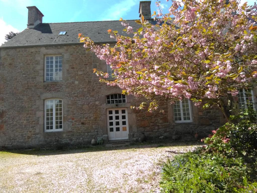 une vieille maison en pierre avec un arbre en face de celle-ci dans l'établissement Le Presbytère, Cotentin, Val de Saire, Fermanville, proximité immédiate mer et forêt, à Fermanville