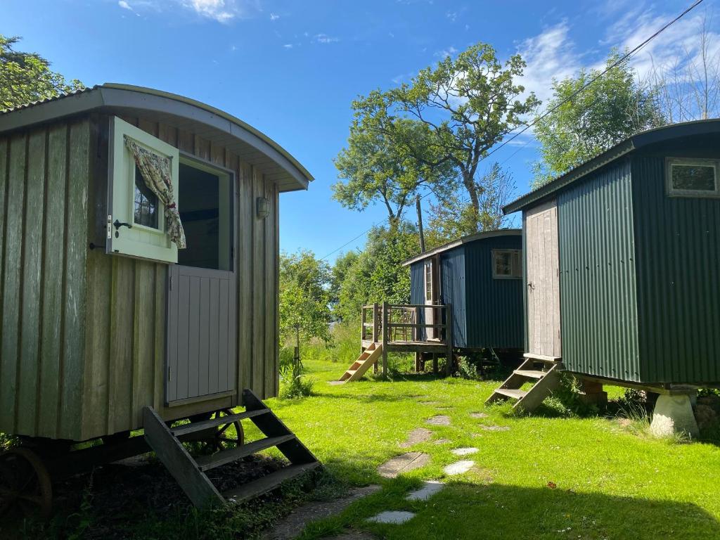 a group of three tiny homes in a field at Shepherds Rest Bruton in Bruton