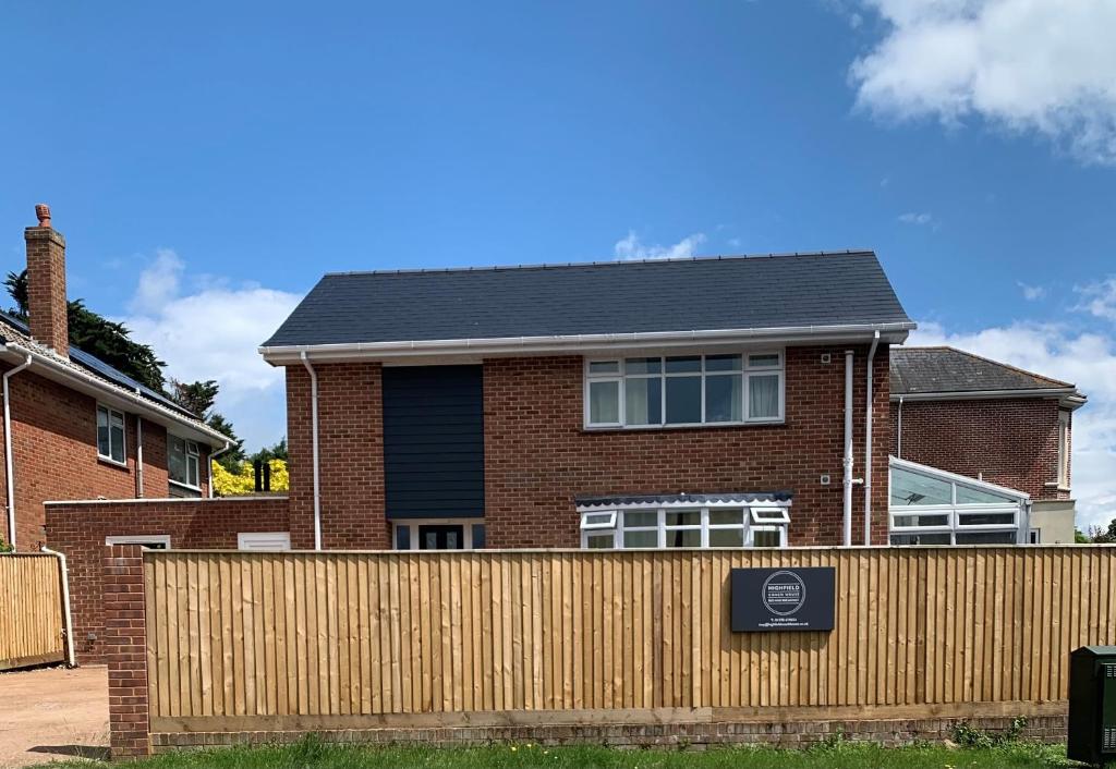 una casa con una valla de madera delante de ella en Highfield Coach House en Lymington