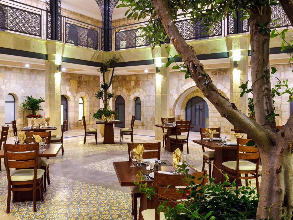 um restaurante com mesas e cadeiras e uma árvore em The Sephardic House Hotel in The Jewish Quarter em Jerusalém